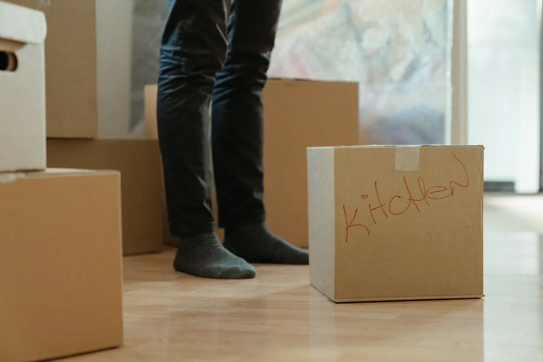 Gepackte und beschriftete Umzugskartons stehen auf dem Dielenboden einer leeren Wohnung