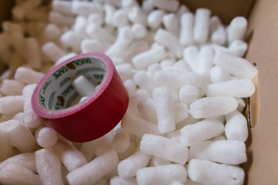 Verpackungschips und eine Rolle Klebeband in einem offenen Karton