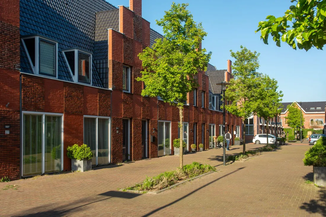Reihenhauszeile aus Backstein mit kleinen Vorgärten und gepflasterter Anliegerstraße